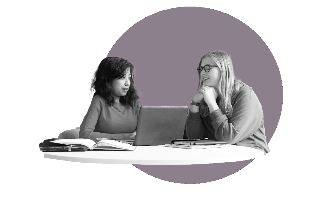 a woman with brown hair and a women with blonde hair and glasses talking over a laptop.